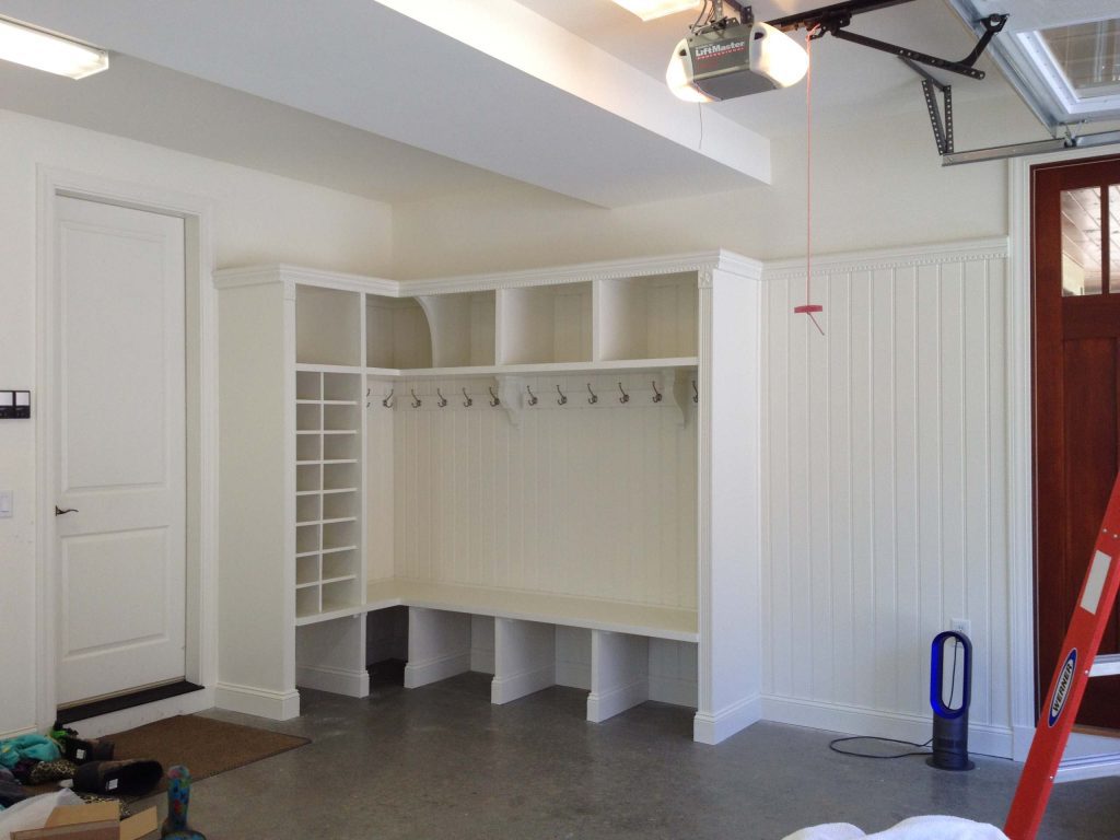 A finished garage that's been transformed into a mudroom. There's storage space for coats and shoes. 