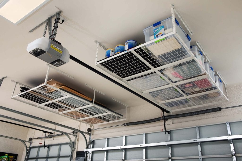 Garage that has overhead racks mounted to the ceiling. The racks have storage bins on them. 